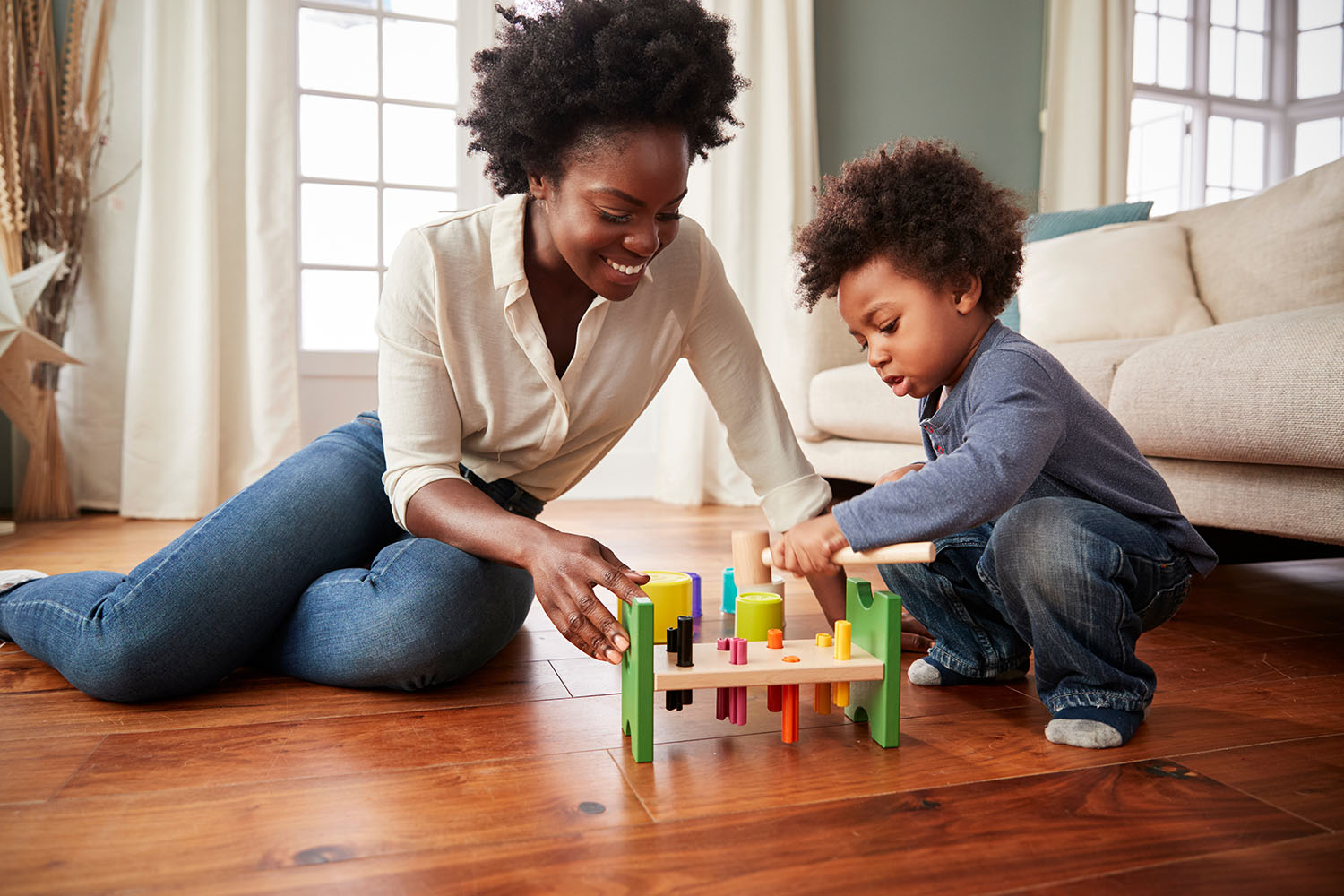 A parent and child playing with wooden toys at home