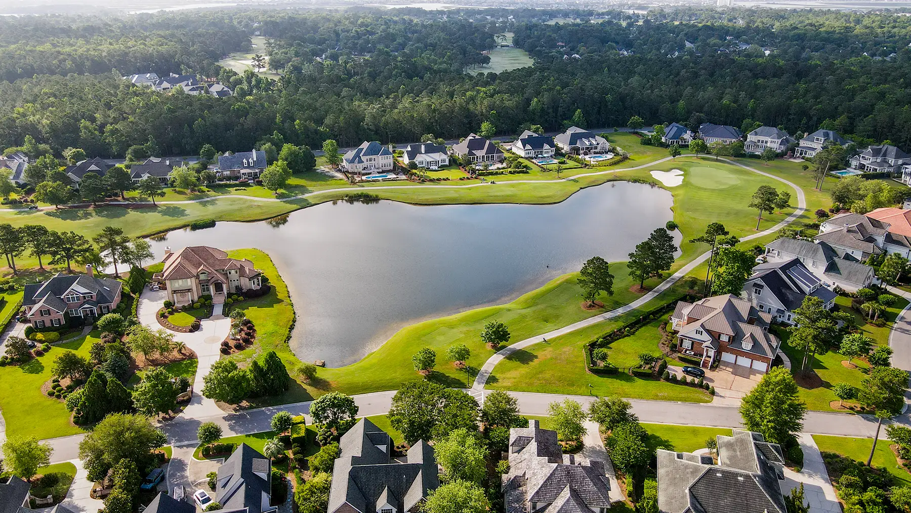 Aerial view of Landfall homes surrounding a pond and golf green