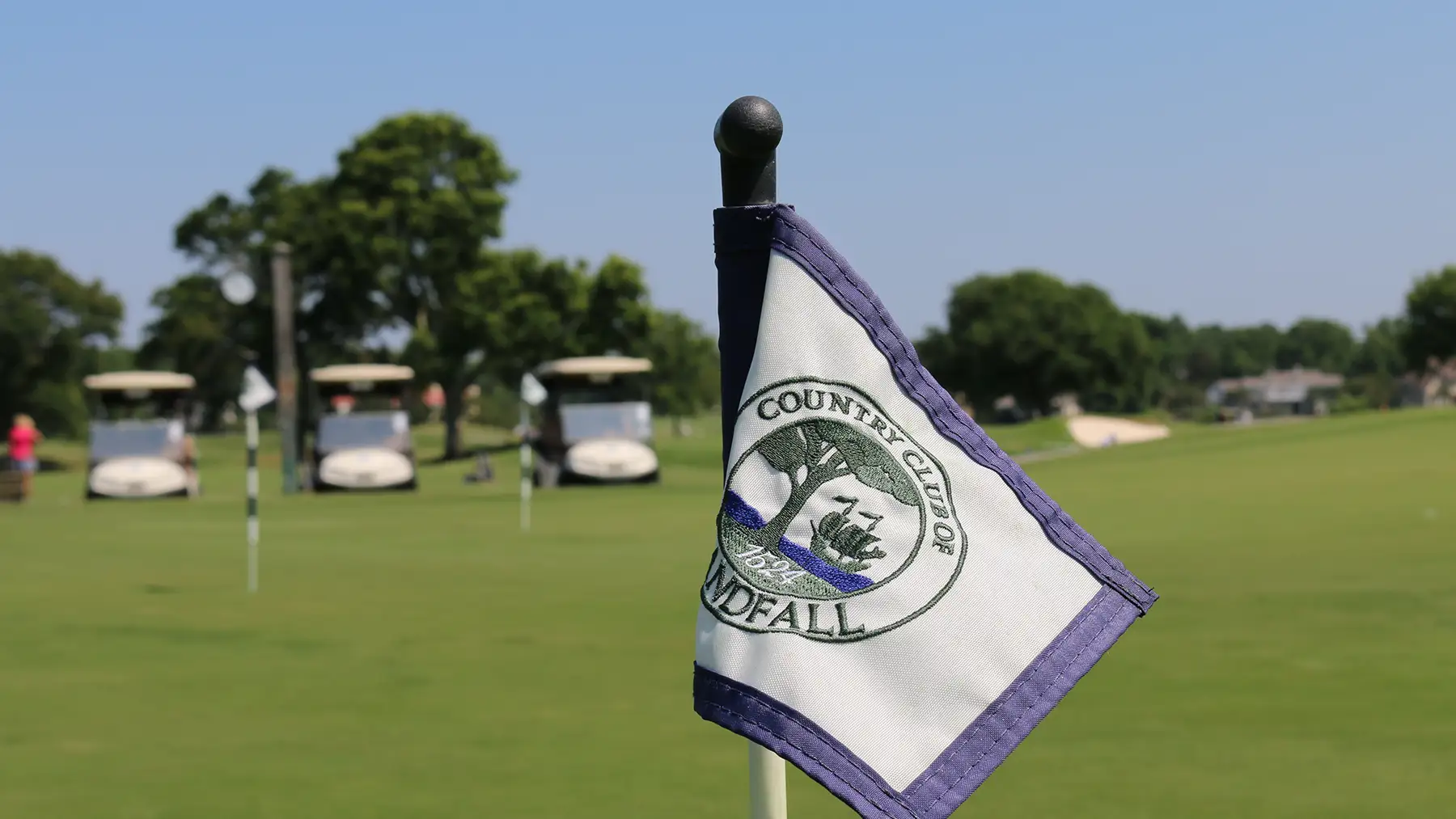 Country Club of Landfall flag beside a putting green and golf carts