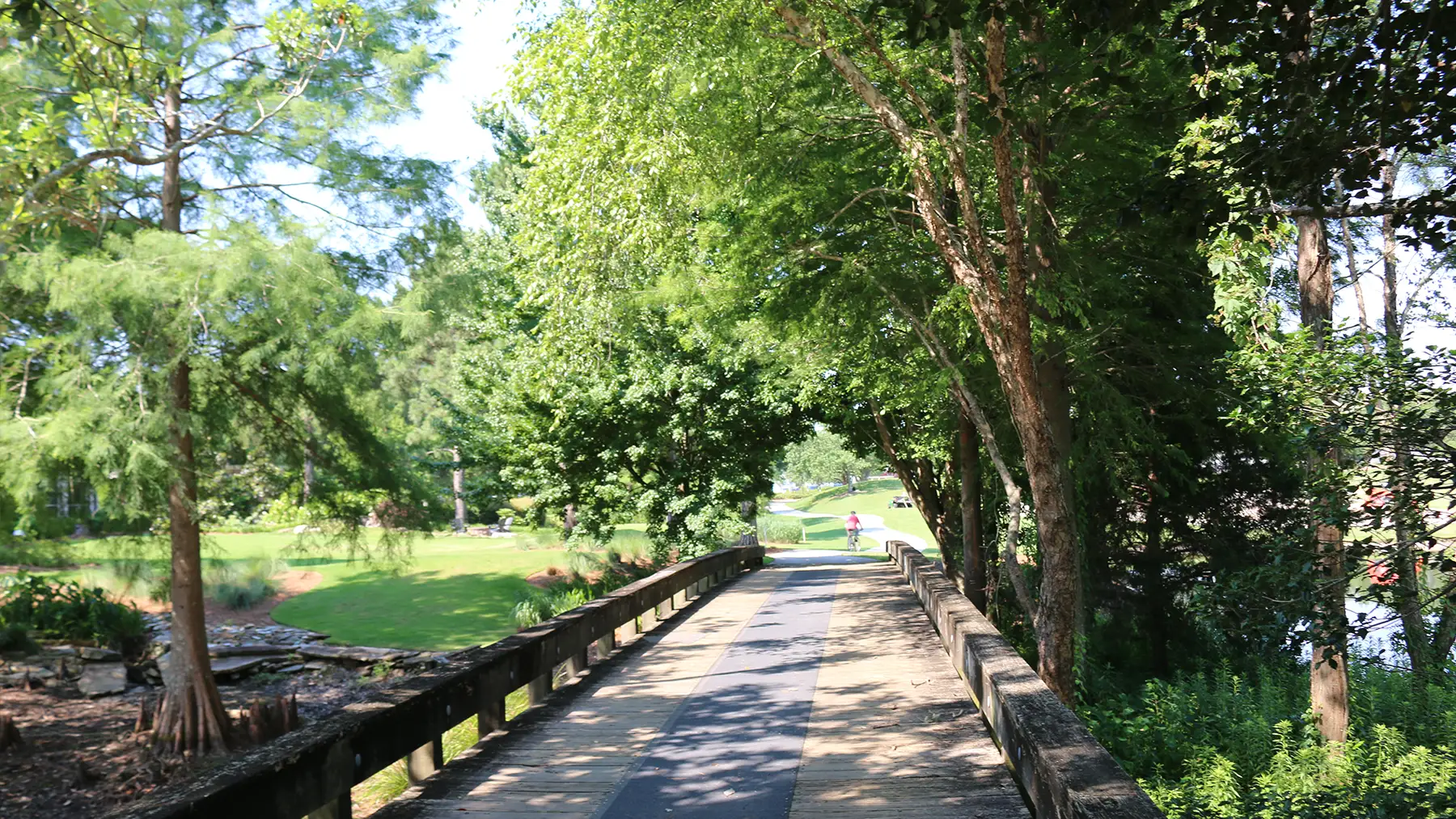 A shaded wooden bridge along a tree-lined path in Landfall