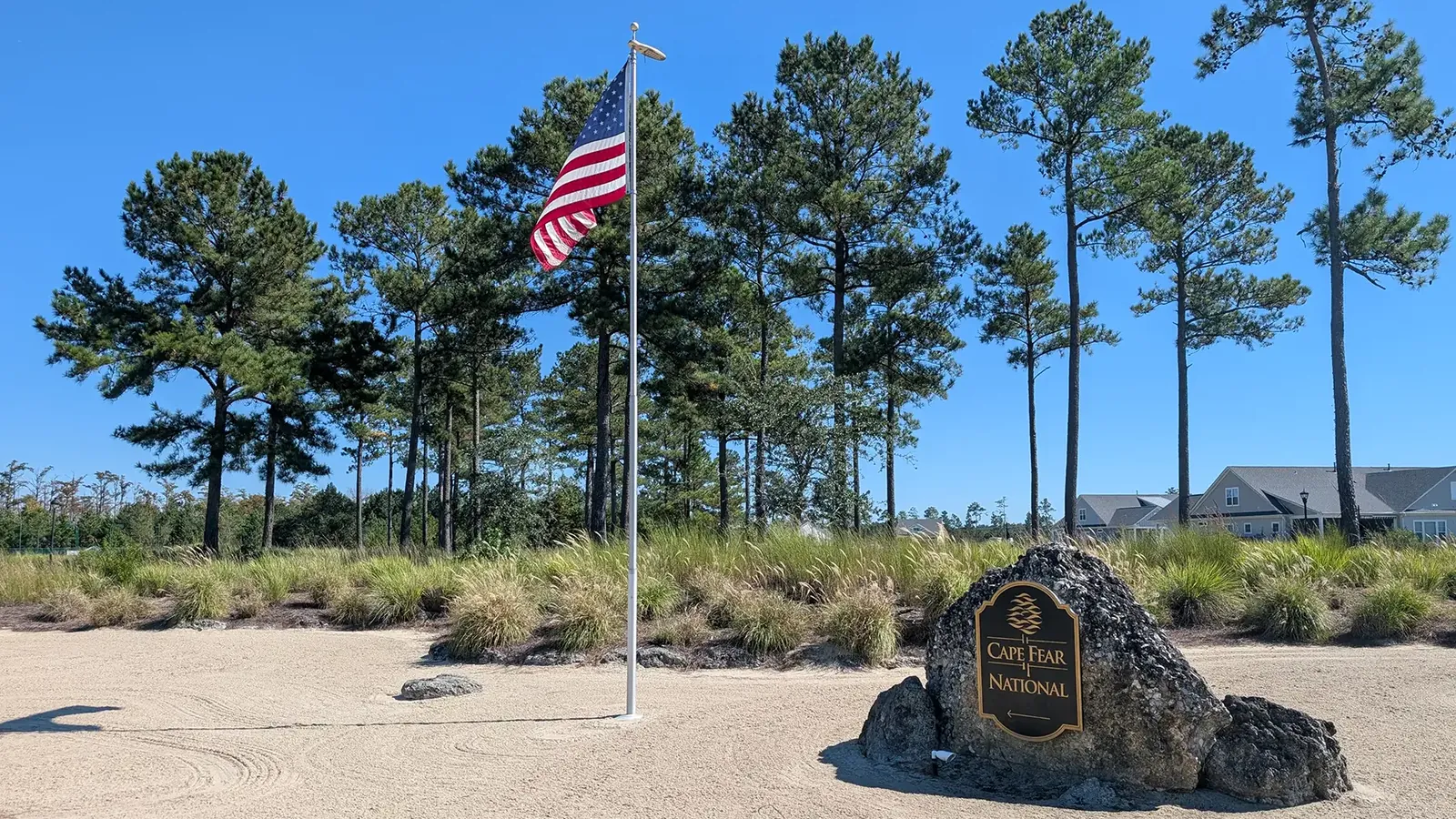 Cape Fear National stone sign beside an American flag and tall pines at Brunswick Forest in Leland, NC