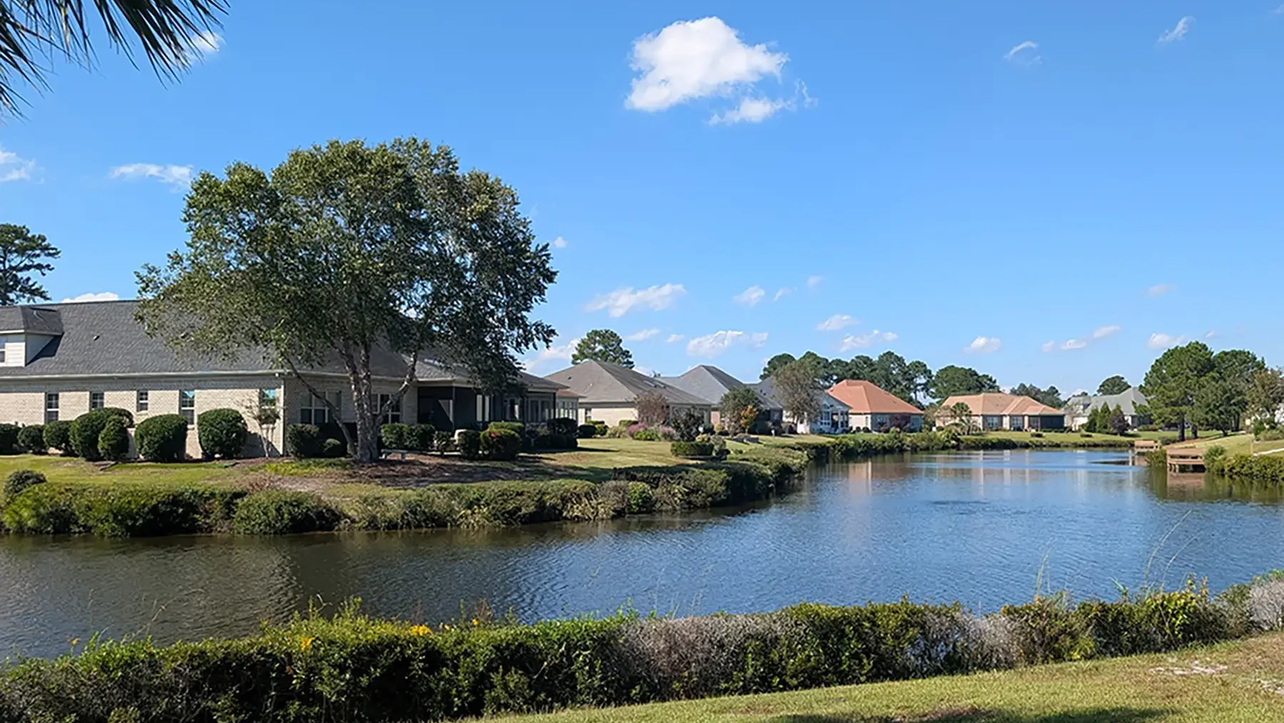 Homes overlooking a calm canal edged with shrubs in Waterford of the Carolinas, Leland, NC