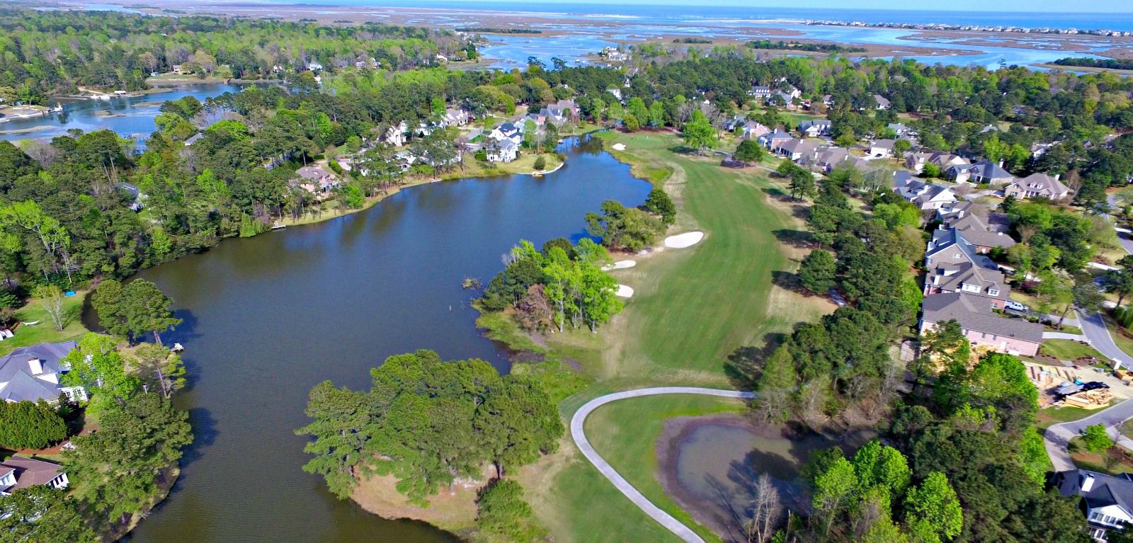 Homes, a pond, and golf fairways with coastal waterways beyond Porters Neck Plantation