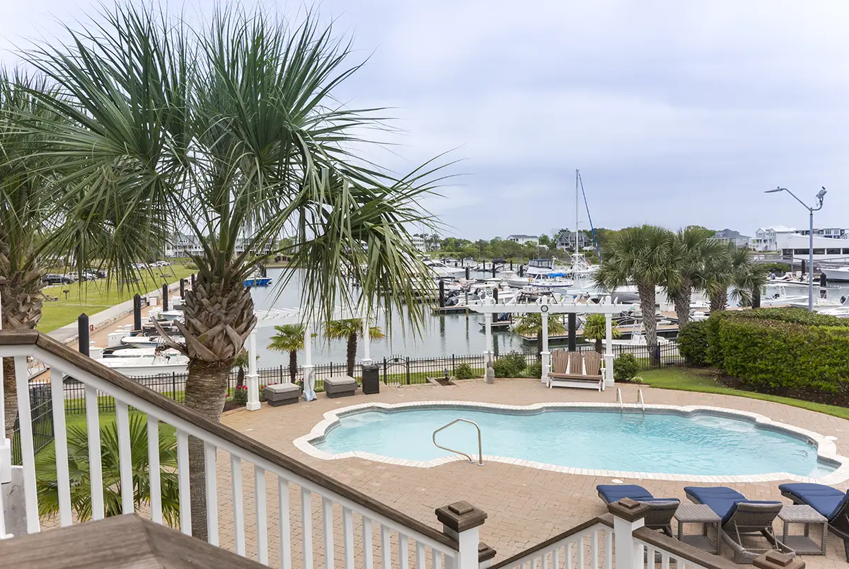 Pool and palm trees overlooking a marina with boats and docks